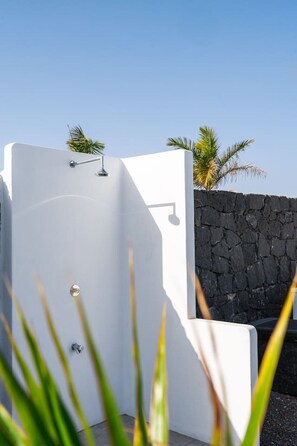 Relax in a serene outdoor shower area with a handheld showerhead and faucet.