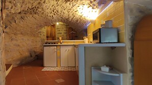 A narrow stone-walled kitchen with a built-in microwave and a small refrigerator. - Cévennes vacations in the heart of nature in a farmhouse apartment (Cendras)
