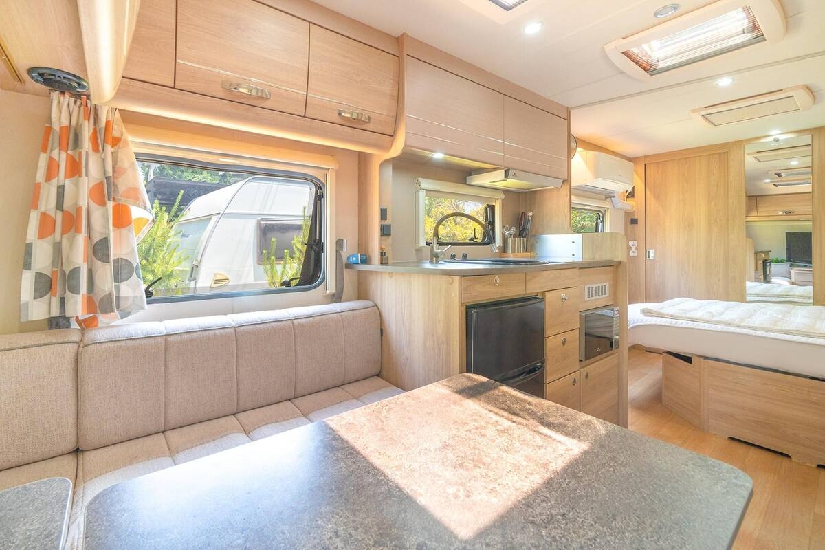 A compact RV kitchen with a built-in stove, a sink, and a small refrigerator.