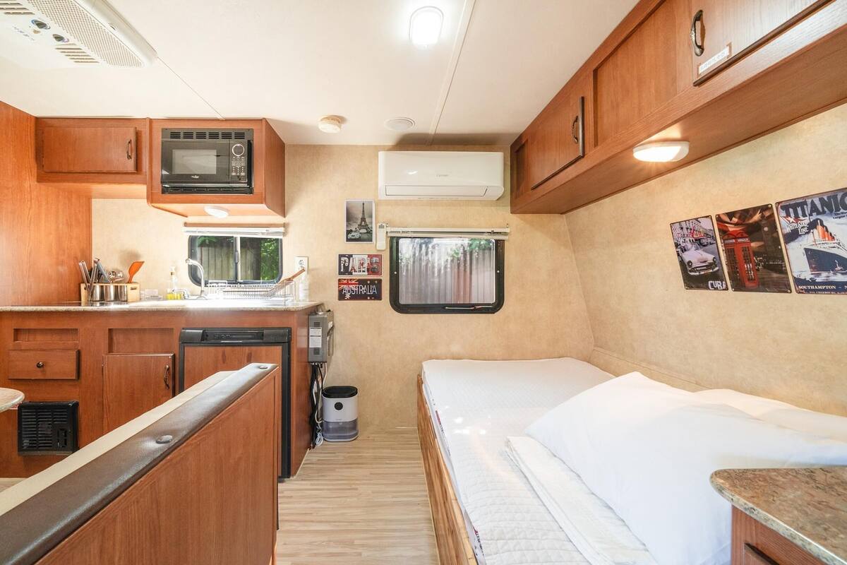 A compact RV kitchen with a microwave, sink, and dishwasher.