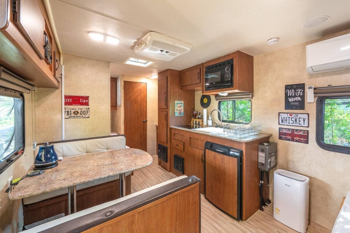 A compact RV kitchen with a sink, stove, and a small refrigerator.