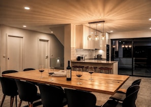 Uma sala de jantar moderna com uma mesa de madeira, cadeiras pretas e uma garrafa de vinho.