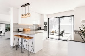 Cozinha moderna com ilha central, banquetas e iluminação pendente.
