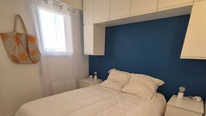 Een slaapkamer met een bed, twee nachtkastjes, een wandkast en een raam met gordijnen.