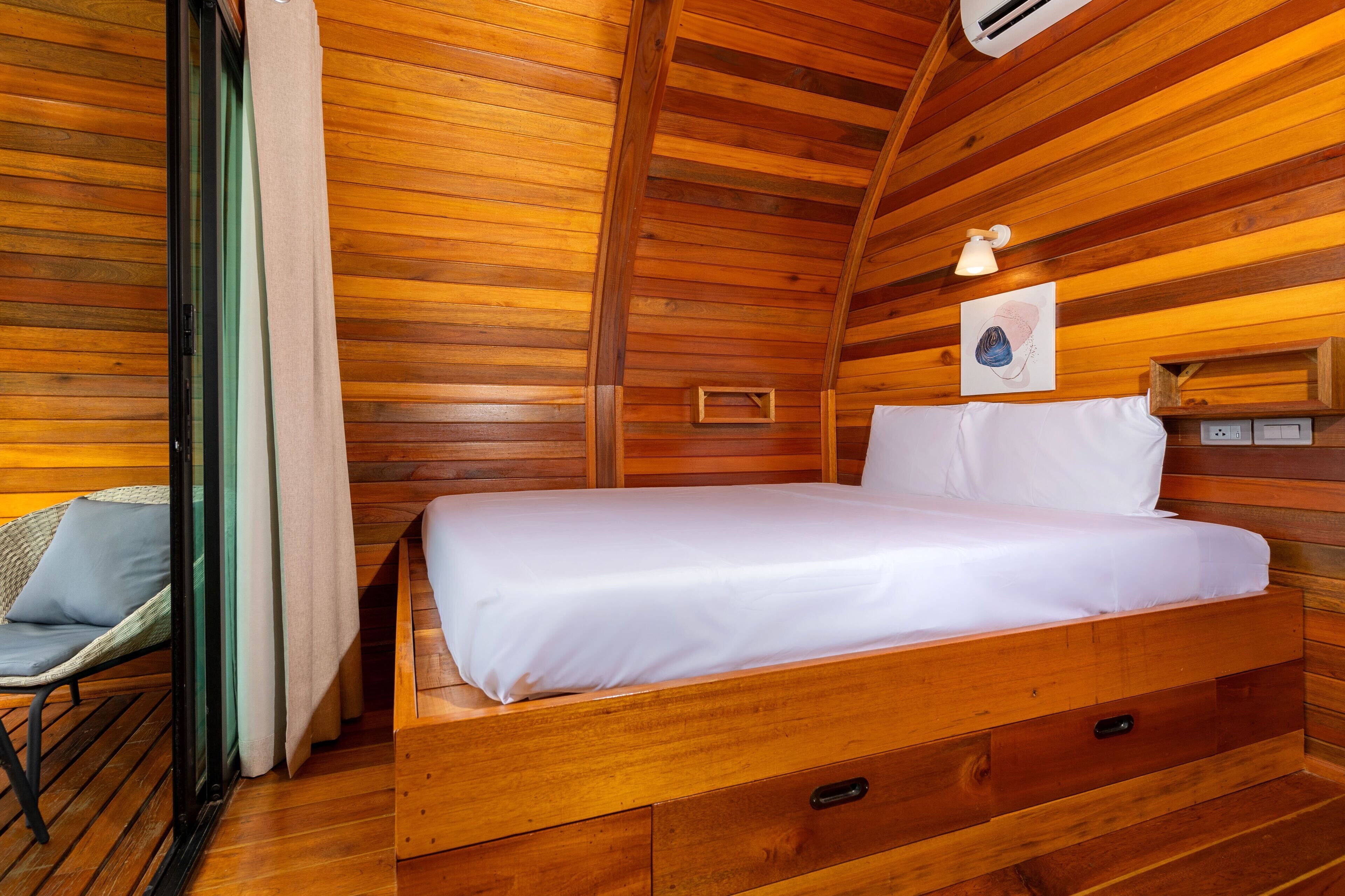 Een houten kamer met een bed, een stoel en een kleine tafel.