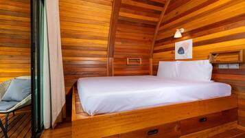 Een houten kamer met een bed, een stoel en een kleine tafel.