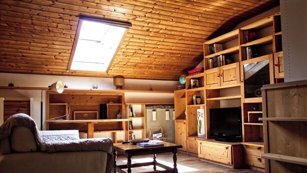 Ein gemütliches Wohnzimmer mit Holzmöbeln, einem Fernseher und Bücherregalen.