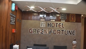 A reception desk with a sign reading "HOTEL GREEN FORTUNE" and clocks displaying times for Delhi, London, and New York. - Hotel Green Fortune (Ahmedabad)
