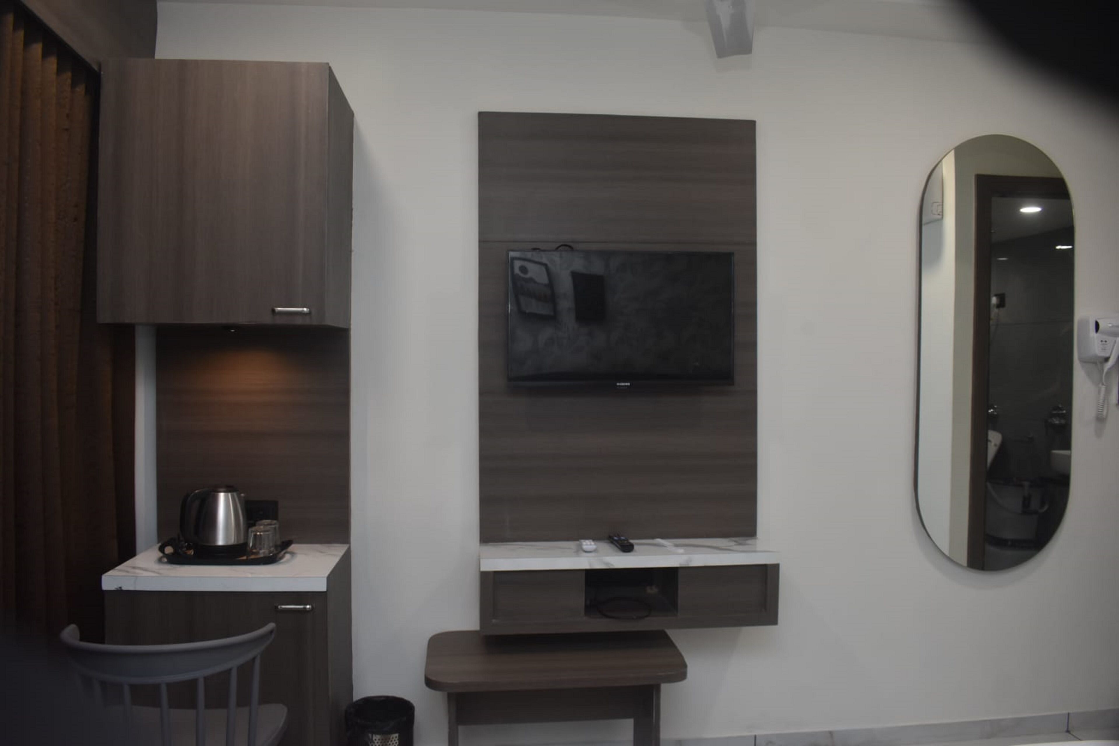 Un baño moderno con tocador de madera, un espejo y un televisor montado.
