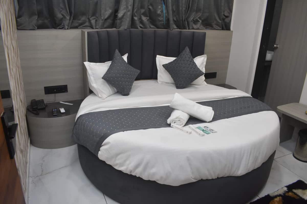 Ein modernes Hotelzimmer mit einem großen Bett, einem Nachttisch und einem Fenster mit Vorhängen.