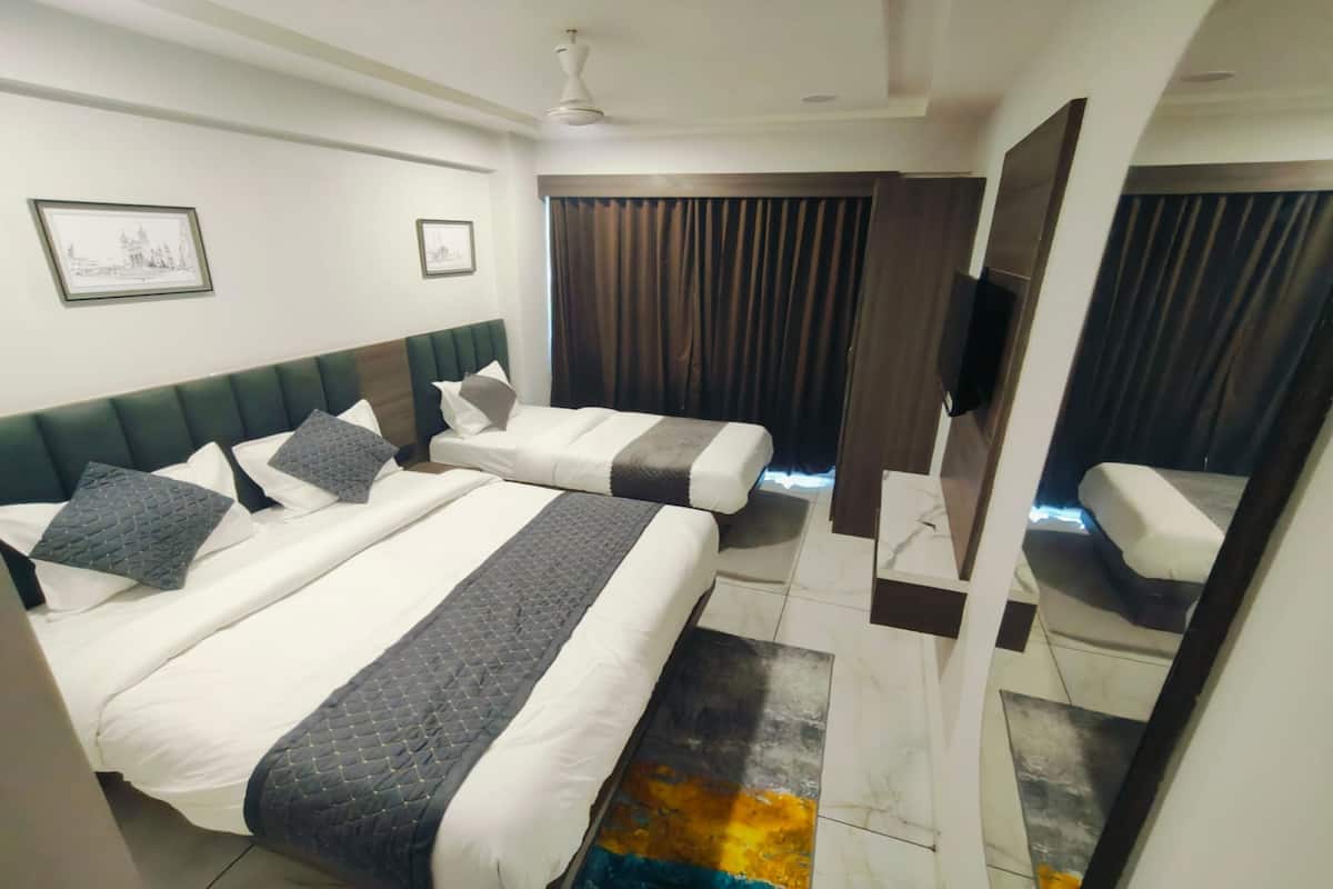 Ein Hotelzimmer mit zwei Betten, einem Flachbildfernseher und einem großen Spiegel.