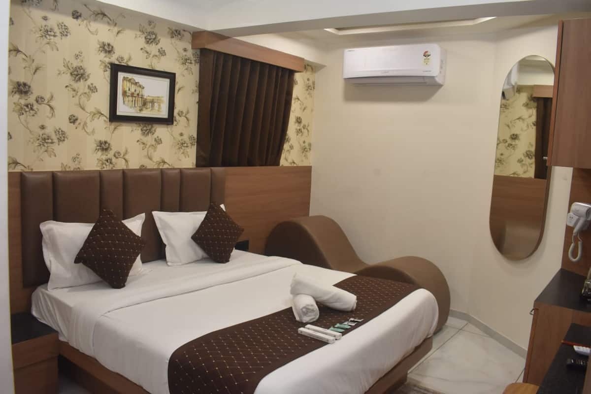 Ein Hotelzimmer mit einem Bett, einem Schreibtisch, einem Sessel, einer Klimaanlage und einem gerahmten Bild an der Wand.