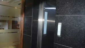 An elevator with a metallic interior and a control panel on the wall. - Hotel Green Fortune (Ahmedabad)