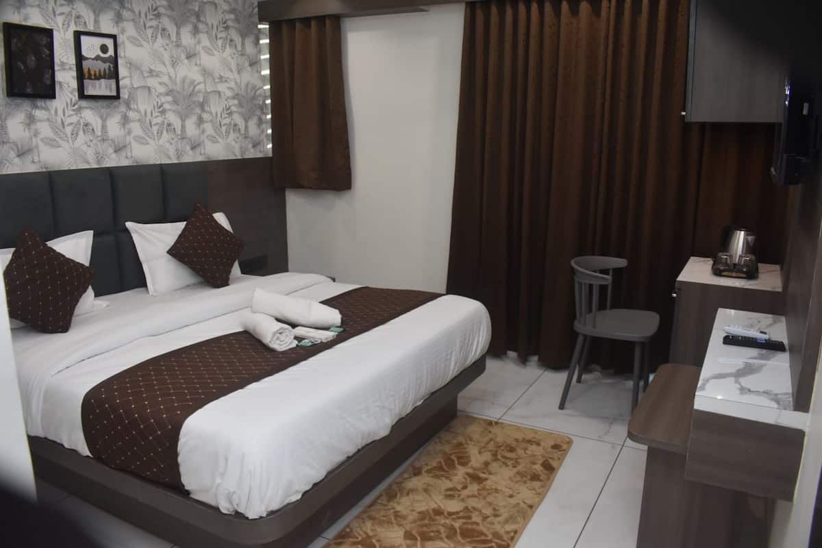 Ein Hotelzimmer mit einem großen Bett, einem kleinen Schreibtisch, einem Sessel und einem Fernseher.
