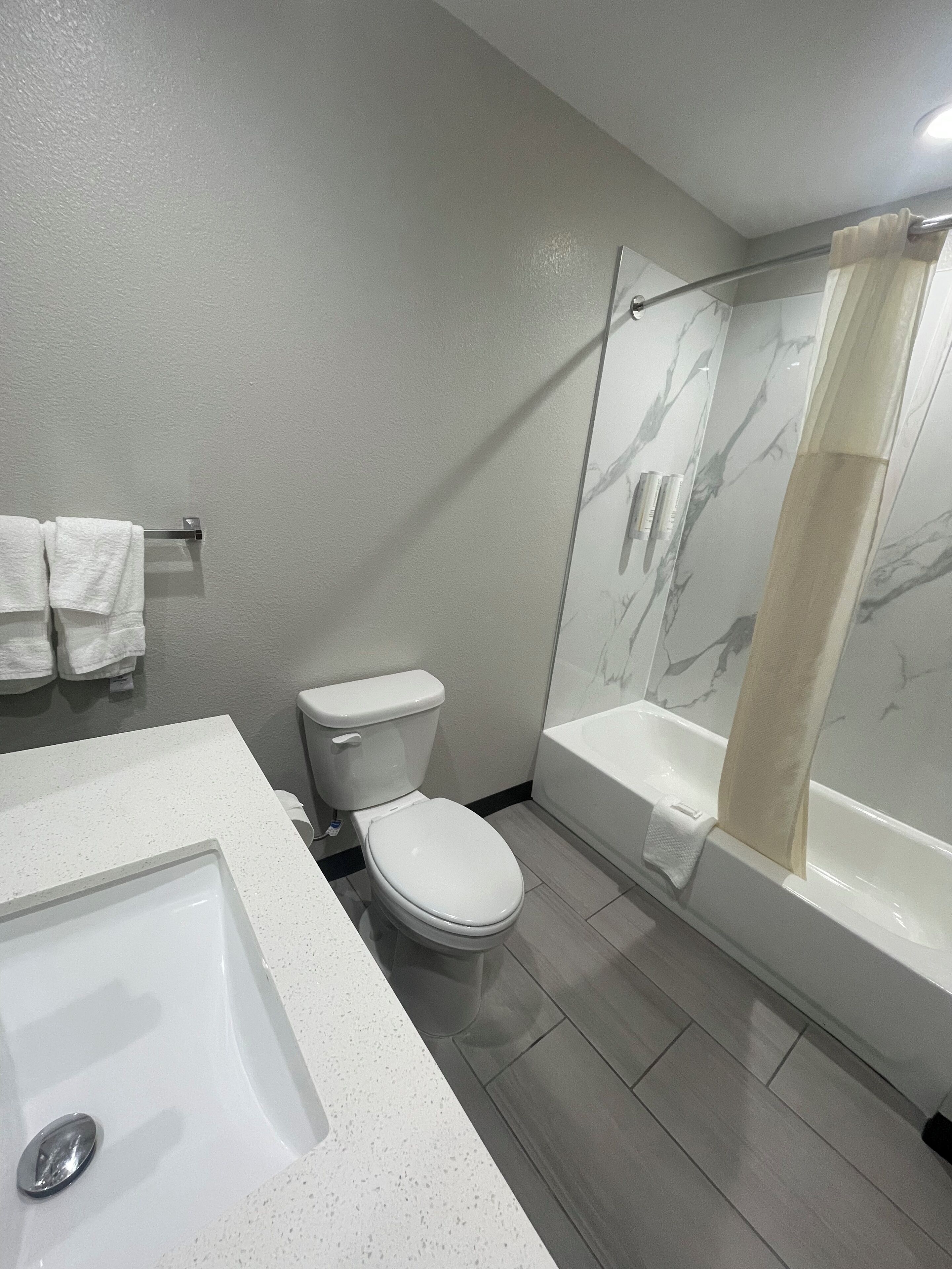 A modern bathroom with a white toilet, a large bathtub with a glass-enclosed shower, and a white sink.
