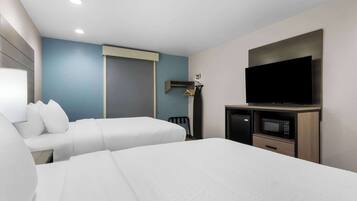 Habitación de hotel con dos camas, televisión, microondas y una pequeña zona de escritorio.