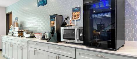 A modern kitchen with a microwave, toaster, and waffle maker on the counter.
