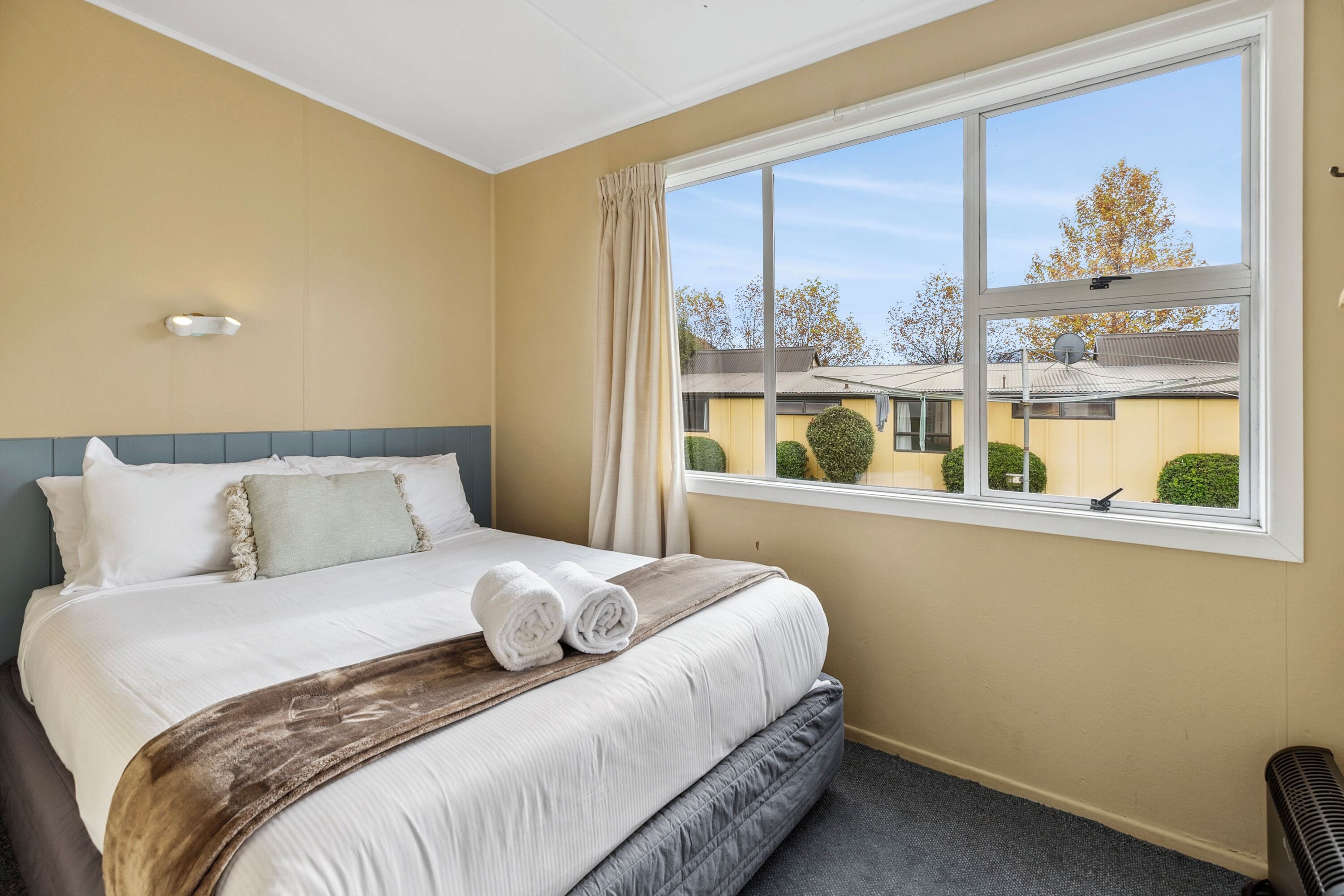 Habitación de hotel con una cama grande, ventana con vistas al exterior y un radiador en el suelo.