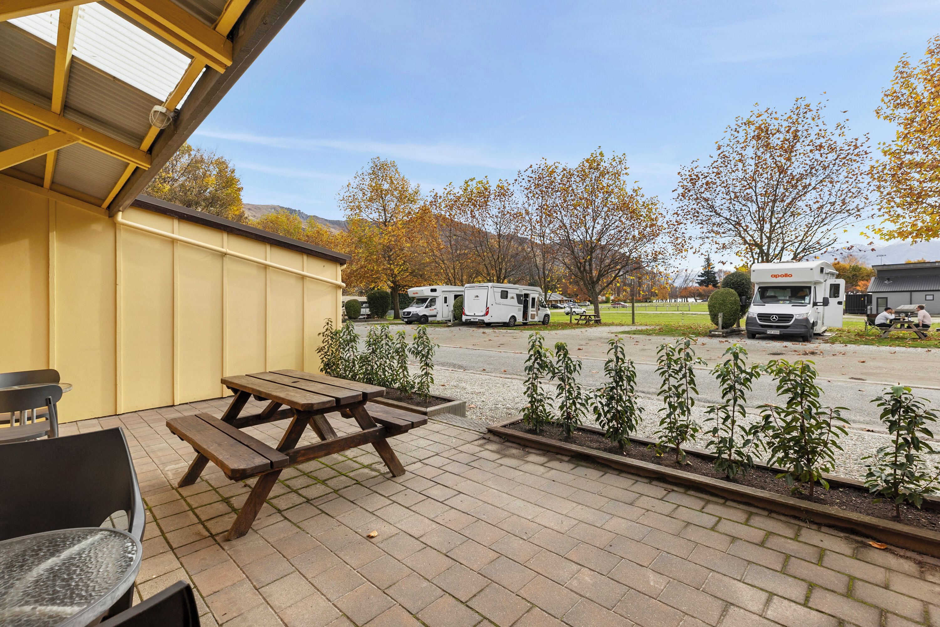 A patio with picnic tables, a covered seating area, and a view of RVs in a parking lot.