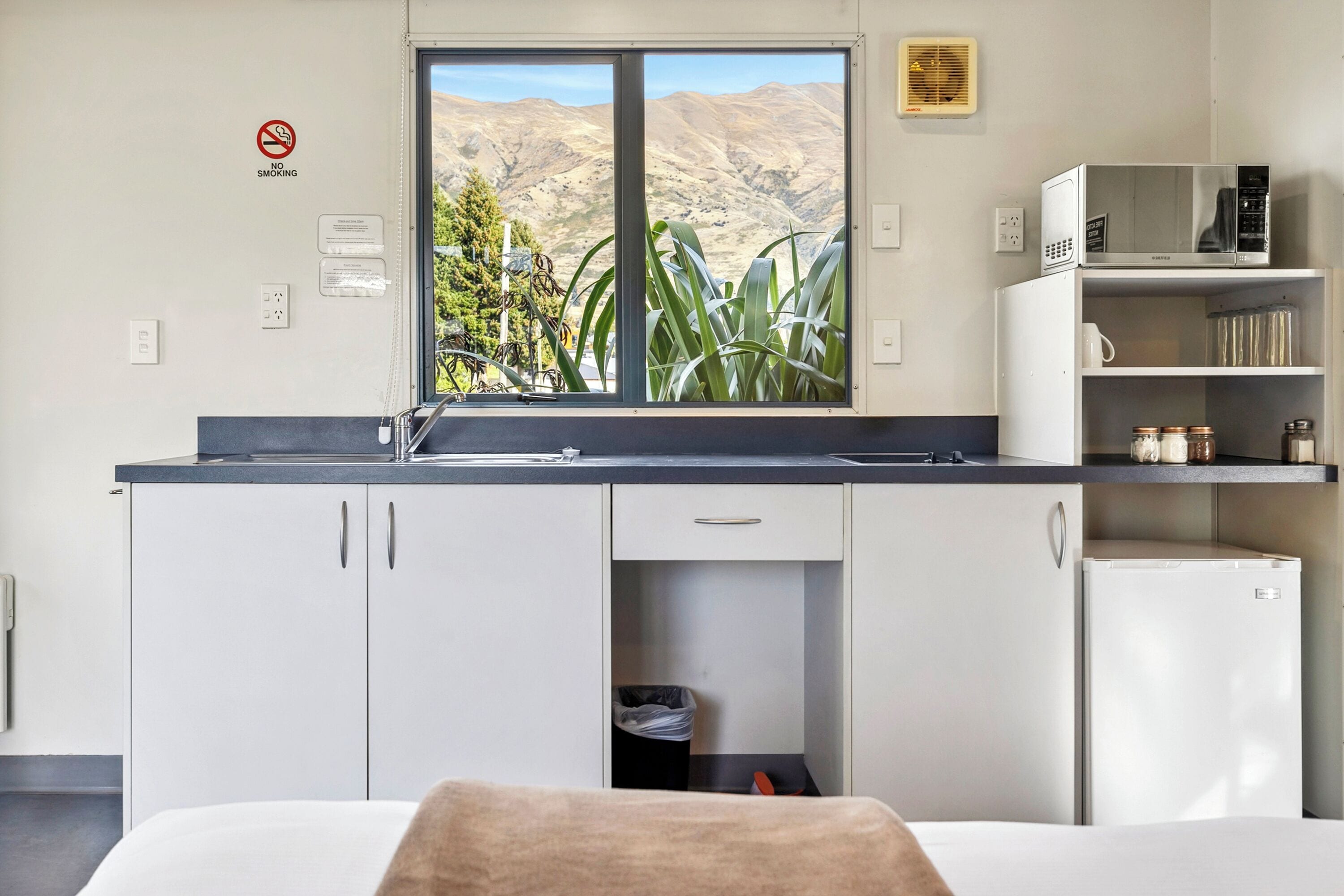 Una cocina moderna con vistas a un paisaje montañoso, microondas y refrigerador.