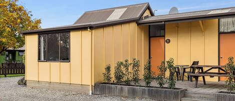 A yellow building with a small patio area, a wooden bench, and a door marked with the number 31.