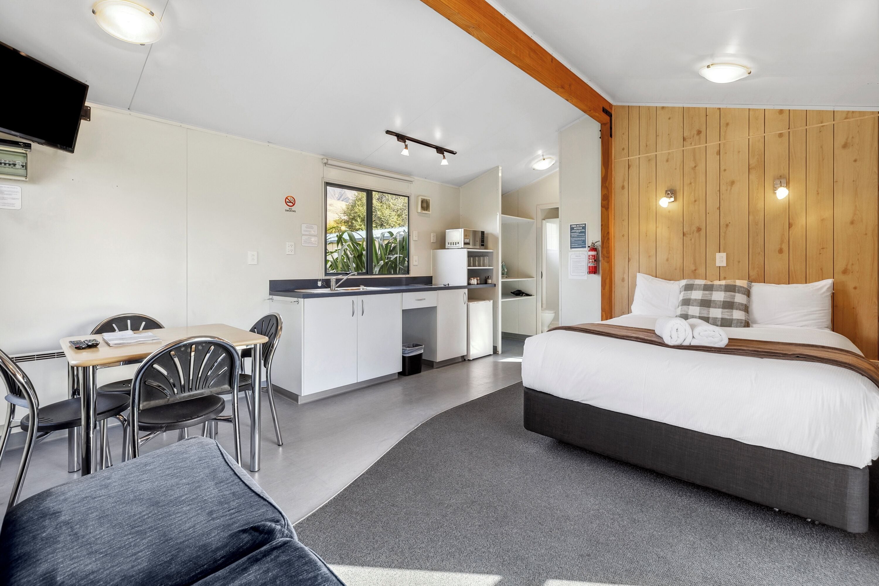 Ein modernes Hotelzimmer mit Bett, Schreibtisch und Küchenzeile.