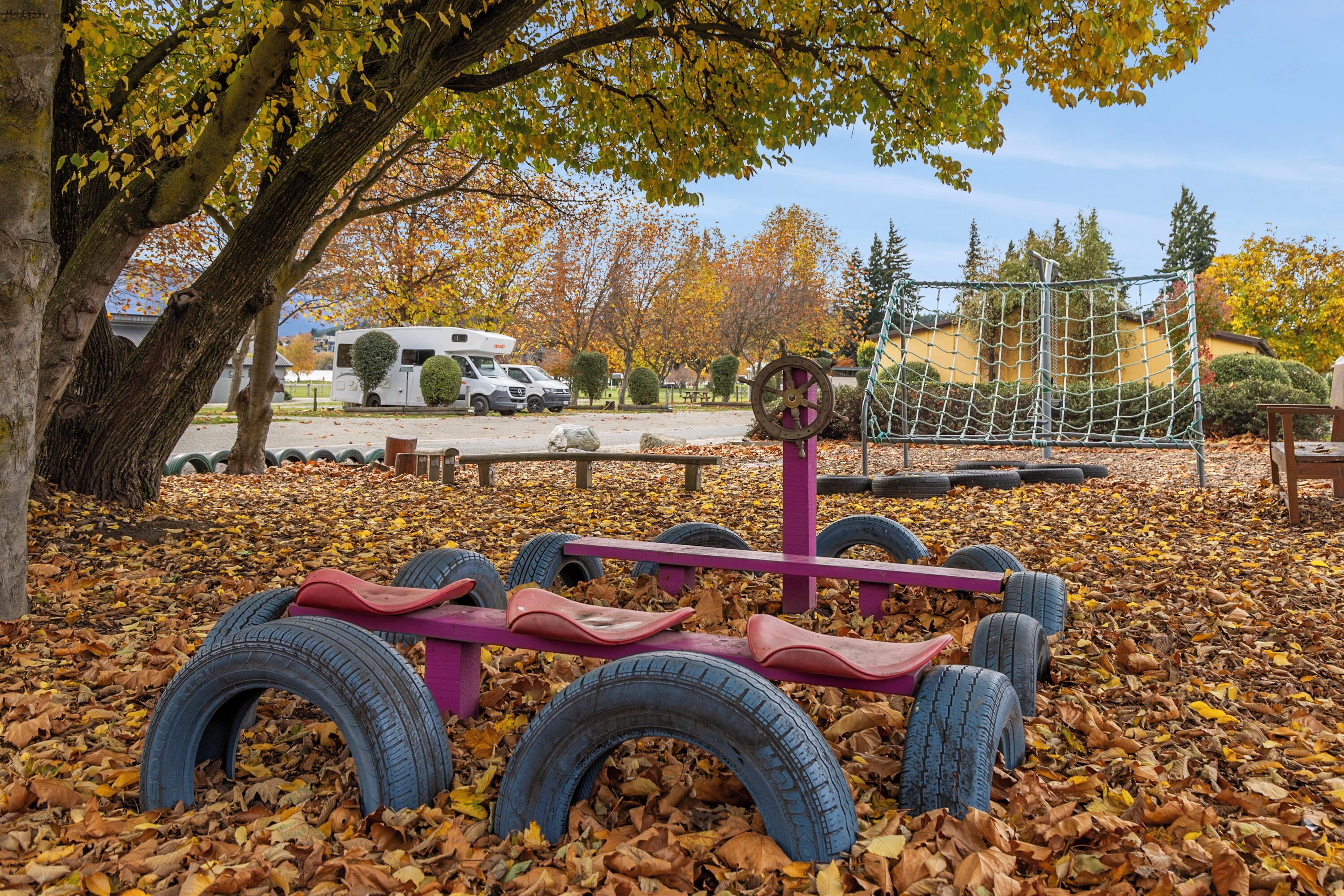 A playground with a seesaw made of tires and a netted climbing structure.
