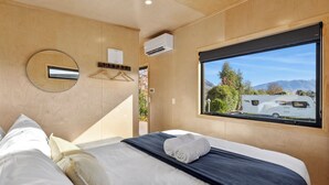 Una camera da letto moderna con una grande finestra, uno specchio rotondo e un letto rifatto con cura.