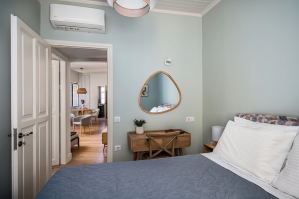 A bedroom with a bed, a dresser, a mirror, and a desk with chairs. - Porta Suites by Konnect, Old Corfu Town (Corfu)