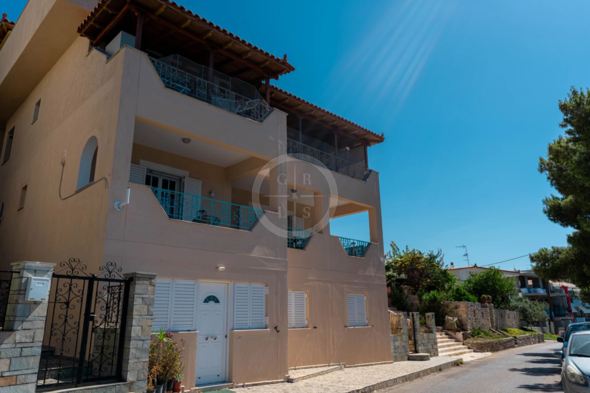 A two-story building with a balcony on the upper floor, a gated entrance, and a clear blue sky.