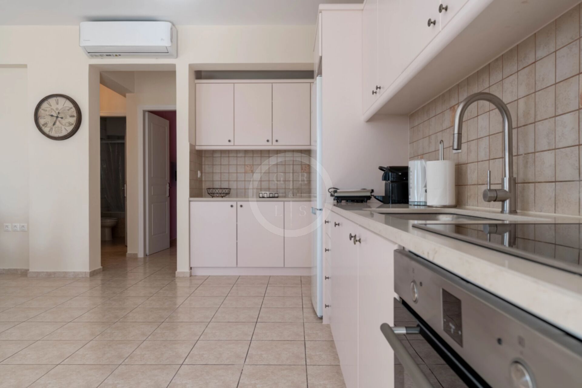 Een moderne keuken met witte kastjes, een roestvrijstalen spoelbak en een inbouwoven.