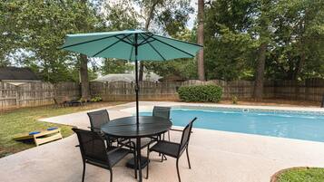 Relax by the pool surrounded by lush greenery and a wooden deck.