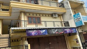 A multi-story building with balconies, a closed shop with a purple banner advertising ice, and a sign for a phone service. - Hotel O Kos Rian (Pallangga)