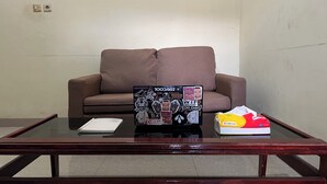 A room with a brown sofa, a glass coffee table with a notebook, and a box of tissues. - Hotel O Kos Rian (Pallangga)