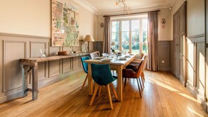 A dining area with a wooden table, teal chairs, and a cityscape painting on the wall. - 18th century residence with Jacuzzi near Paris (Mennecy)