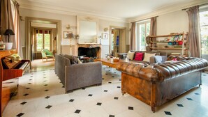 A spacious living room with a fireplace, a piano, and a leather sofa. - 18th century residence with Jacuzzi near Paris (Mennecy)