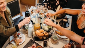 A group of people toasting with champagne glasses at a table with croissants, bread, and a variety of condiments. - Almhof Alpin Apartments & Spa (Dienten am Hochkoenig)