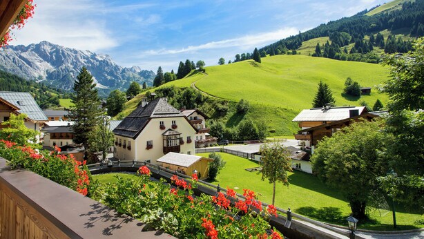 A scenic view of a mountain village with traditional houses, a well-maintained lawn, and a clear sky. - Almhof Alpin Apartments & Spa (Dienten am Hochkoenig)