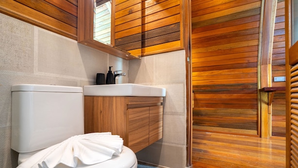 A bathroom with a wooden vanity, a toilet, and a shower area. - Tropical Chalet 3BR Pool Villa Pasak 3  (Choeng Thale)