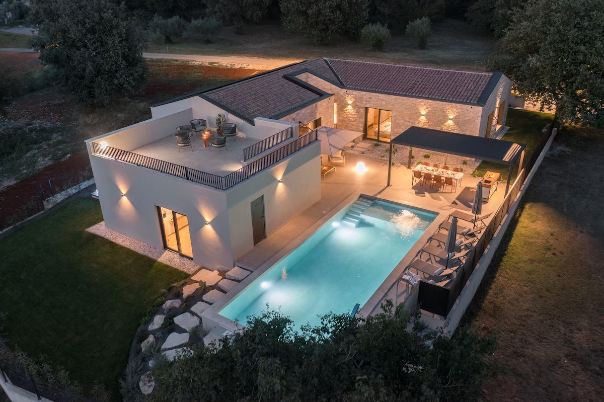 A modern house with a swimming pool, outdoor seating, and a well-lit patio area.