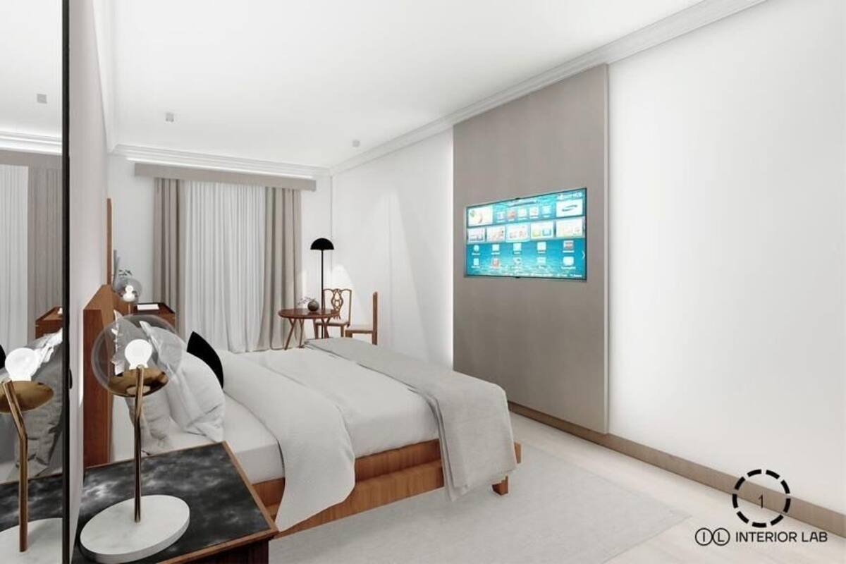 A modern hotel room with a bed, bedside table, lamp, and a digital display on the wall.