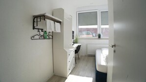 Une petite pièce comprenant un lit, un bureau et un radiateur.