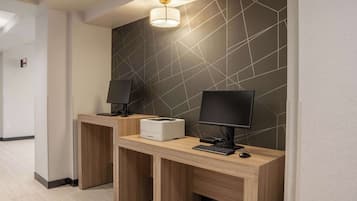 A modern reception desk with two computer stations, a printer, and a wall-mounted lamp.