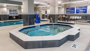 Un área de piscina de hotel con un jacuzzi, sillas de descanso y un espacio de estar.