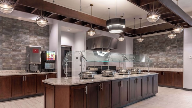 Una cocina moderna con una isla central, electrodomésticos de acero inoxidable e iluminación colgante.