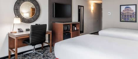 Une chambre d’hôtel équipée d’un bureau, d’une chaise, d’une télévision et de deux lits.