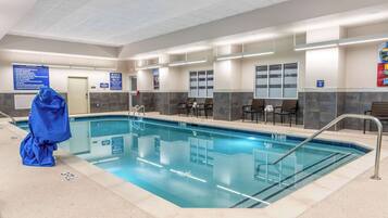 A pool area with a clear pool, seating along the sides, and a covered area with a blue canopy.