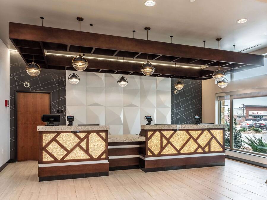 A reception area with a modern design, featuring a geometric wall pattern, a wooden reception desk, and pendant lighting.