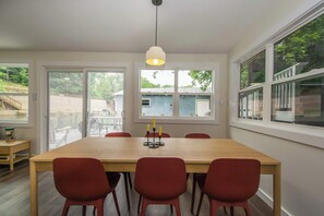 Un coin repas avec une table en bois, des chaises rouges et un luminaire suspendu.