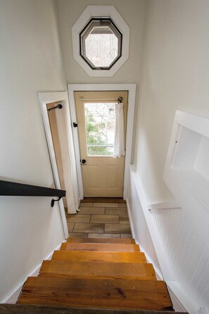 A staircase with wooden steps leading to a door with a window above it.